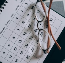 Monthly calendar with glasses on top of it