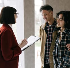 Couple talking to woman with clipboard