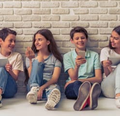 children sitting and looking happy in front of a brick wall
