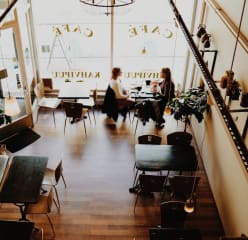 two women sit in a cafe talking and drinking