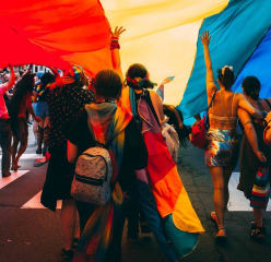 people marching down a road with a giant pride flag overhead