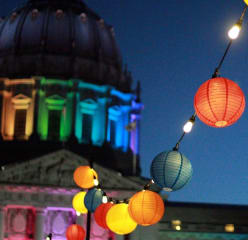 The san francisco city hall at night lit in the rainbow colors of the pride flag.
