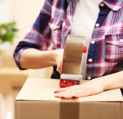 A women is packing a box with tape