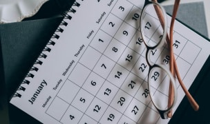 Monthly calendar with glasses on top of it