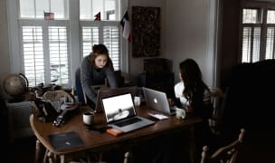 2 students working on their laptops in their student apartment