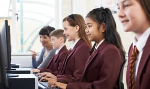 children wearing school uniforms, sitting in front of computers