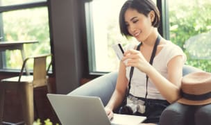 woman holding a credit card to make a payment on her laptop