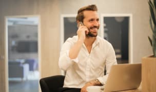 a happy tattooed man talks on a phone