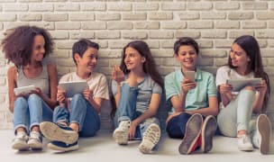 children sitting and looking happy in front of a brick wall