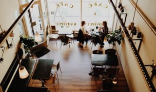 two women sit in a cafe talking and drinking