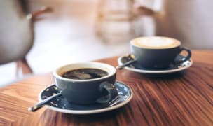 2 cups of coffee in blue mugs sitting on a wooden table