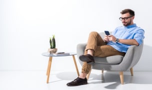 a man is sitting on an armchair looking at his phone