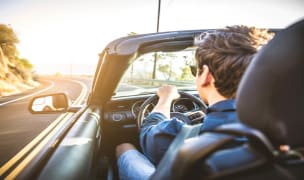 man driving down the road in an open top convertible