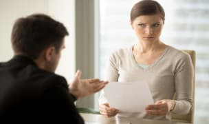 woman holding a paper staring at a man explaining a rental scam