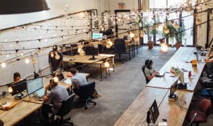 People working in an open office space with monitors and wide desks
