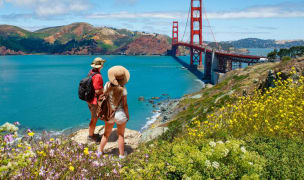 man and woman standing on a trail overlooking the SF Bay and Golden Gate Bridge