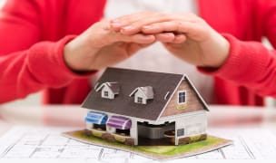 renters insurance closeup of female relator hands showing new house model to client concept of real estate purchase and insurance