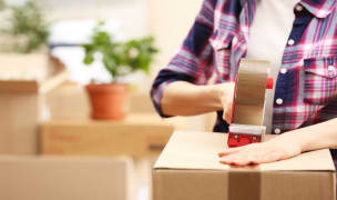 A women is packing a box with tape