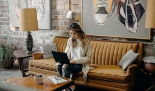 A woman sitting in her living room couch working on her laptop.