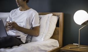 a man relaxing at home holding a cup with a laptop on his lap