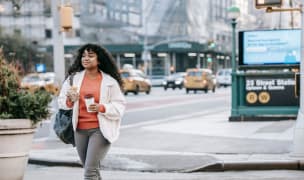 young woman walking in new york city with coffee