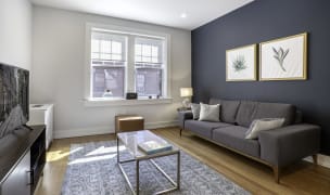 furnished apartment living room with a dark grey accent wall a marble coffee table and a TV