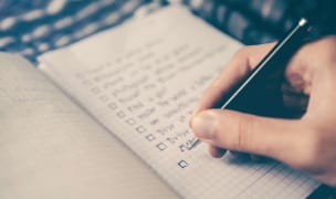 hand holding a pen writing a checklist in a journal