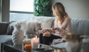 A lady and a dog sit on the couch