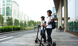 Two women riding electric scooters