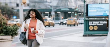 young woman walking in new york city with coffee