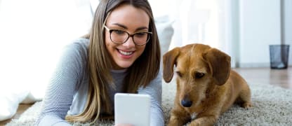 woman sitting on the floor with her dog taking a picture
