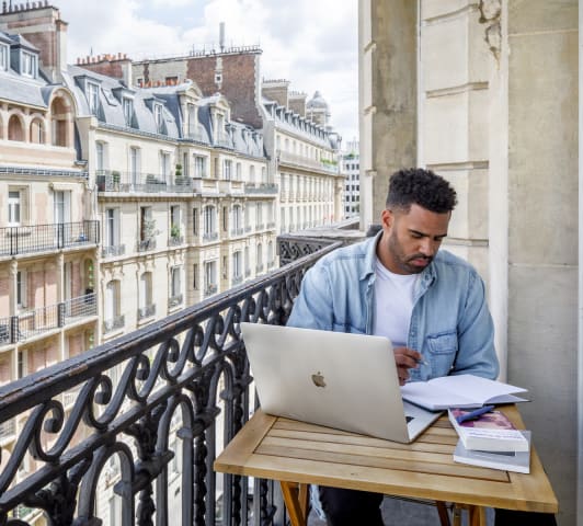 Man working on balcony at a Blueground apartment in Paris