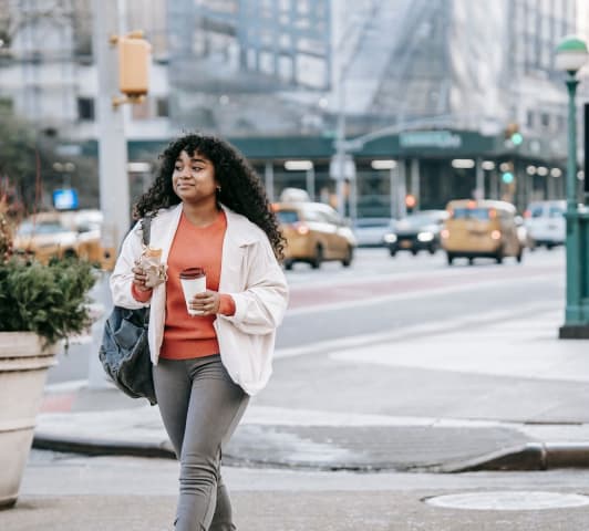 young woman walking in new york city with coffee