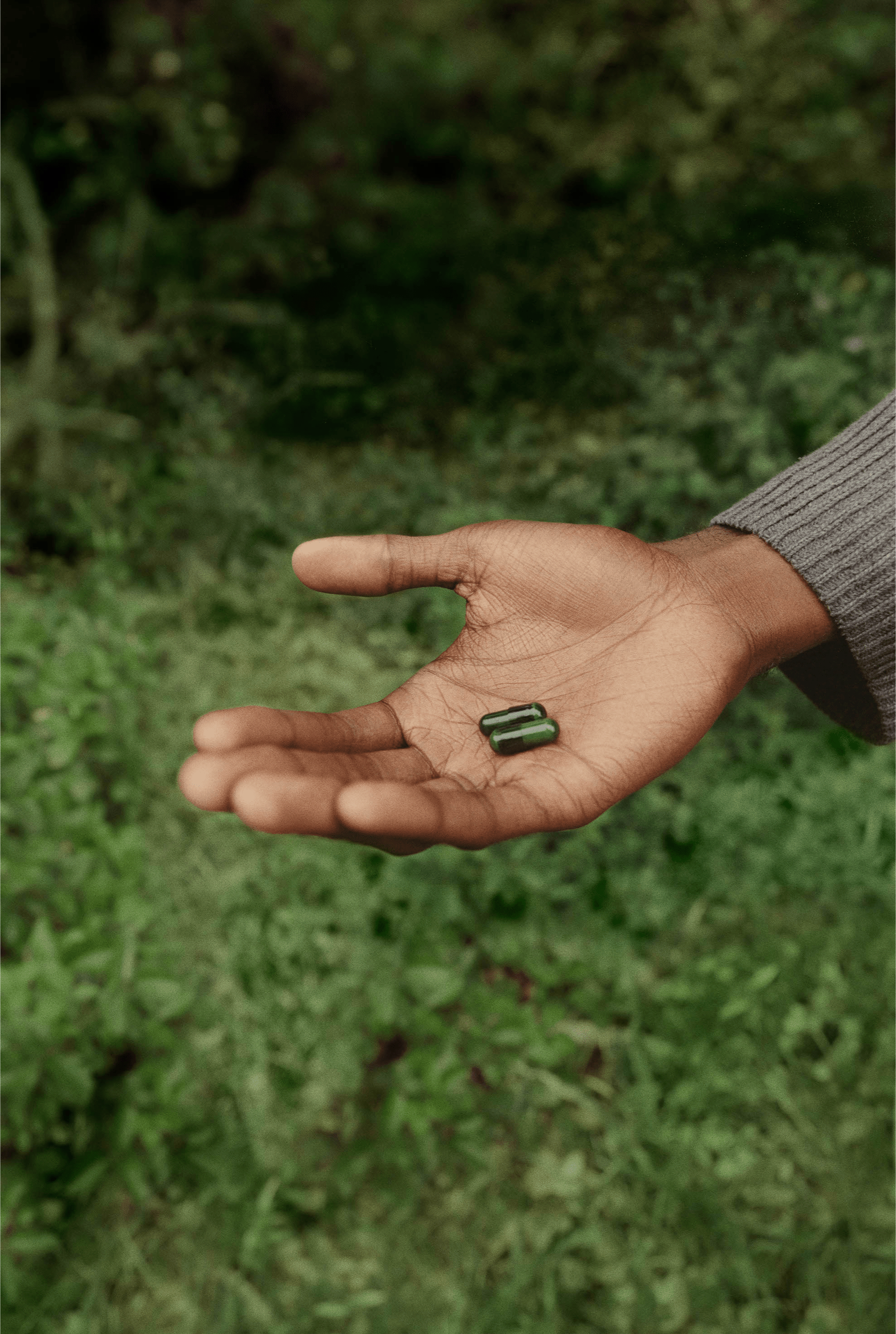 open hand holding green pills outside