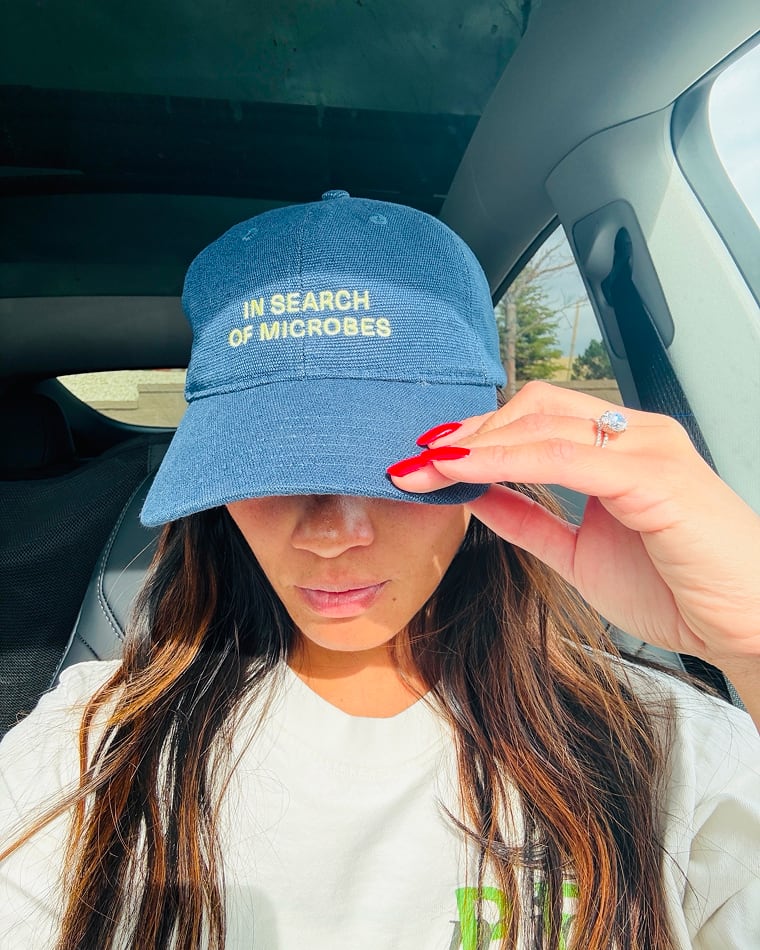 A Seed team member wearing a cap that reads "In search of microbes"