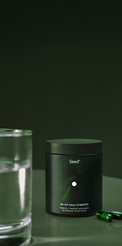 DS-01 Daily Synbiotic jar and capsules beside a glass of water