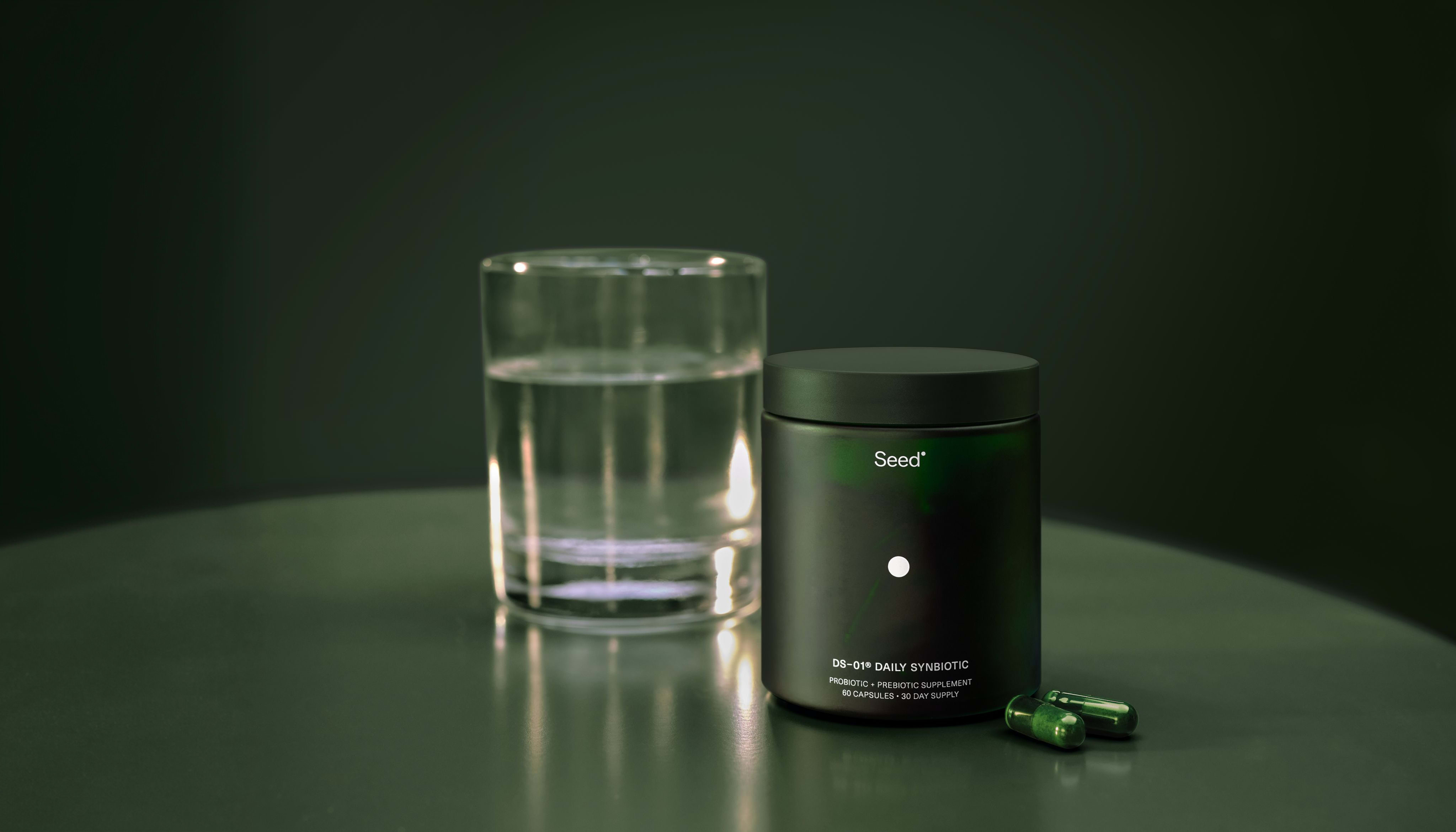 DS-01 Daily Synbiotic jar and capsules beside a glass of water
