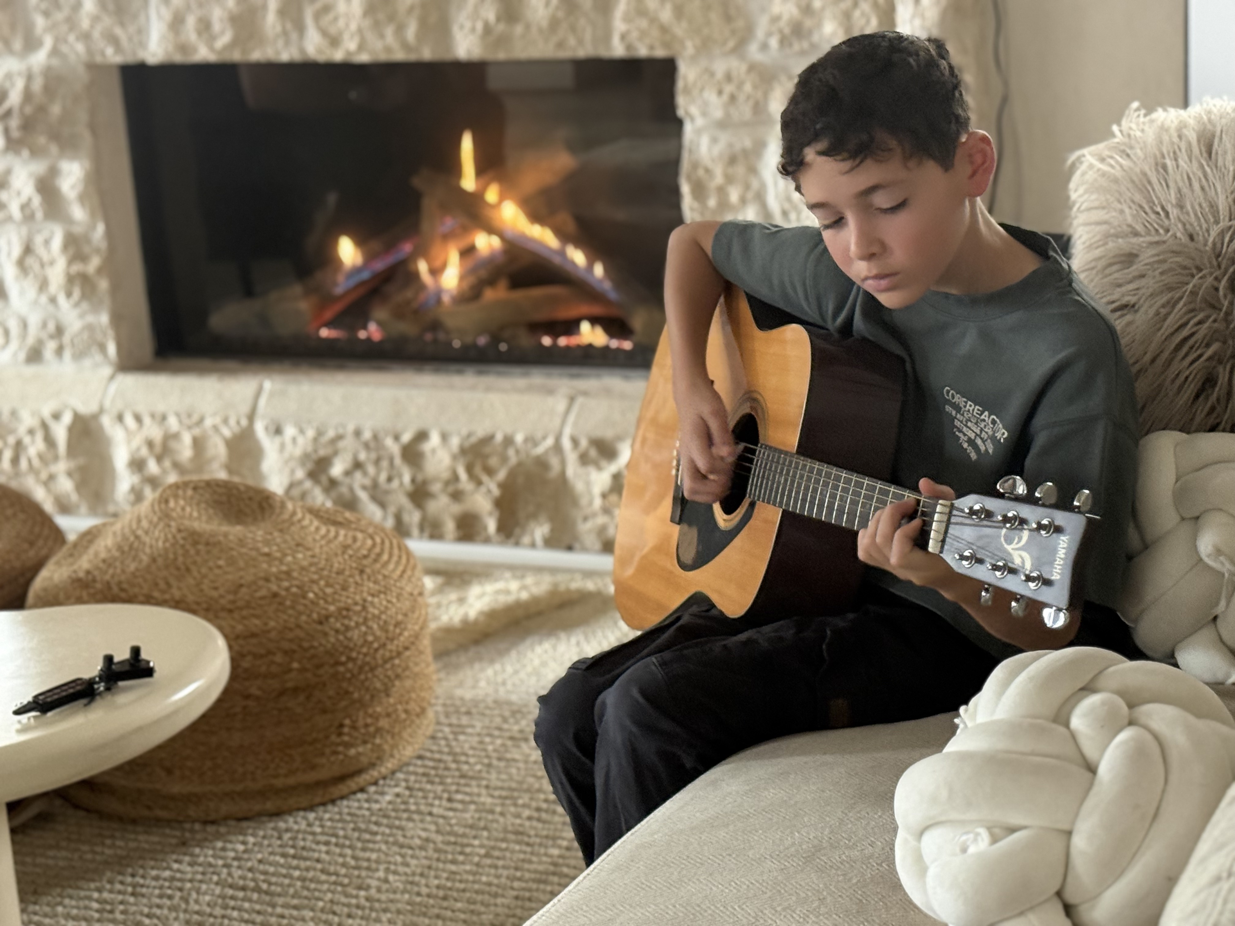 Boy playing guitar by the fireplace