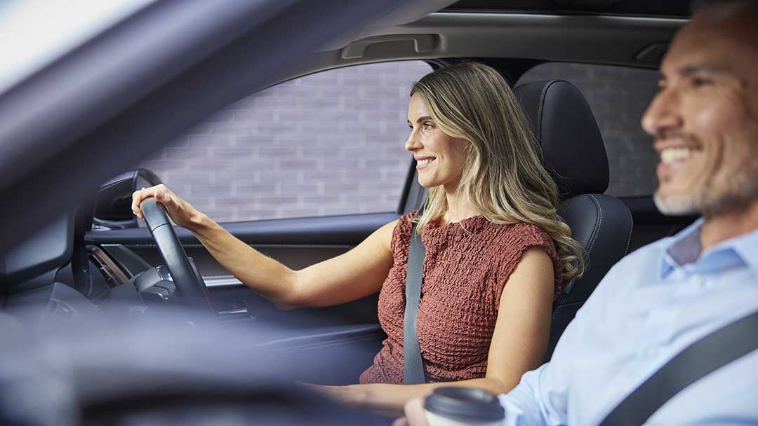 Woman driving her Mazda CX-60 SUV with a man in the passenger seat