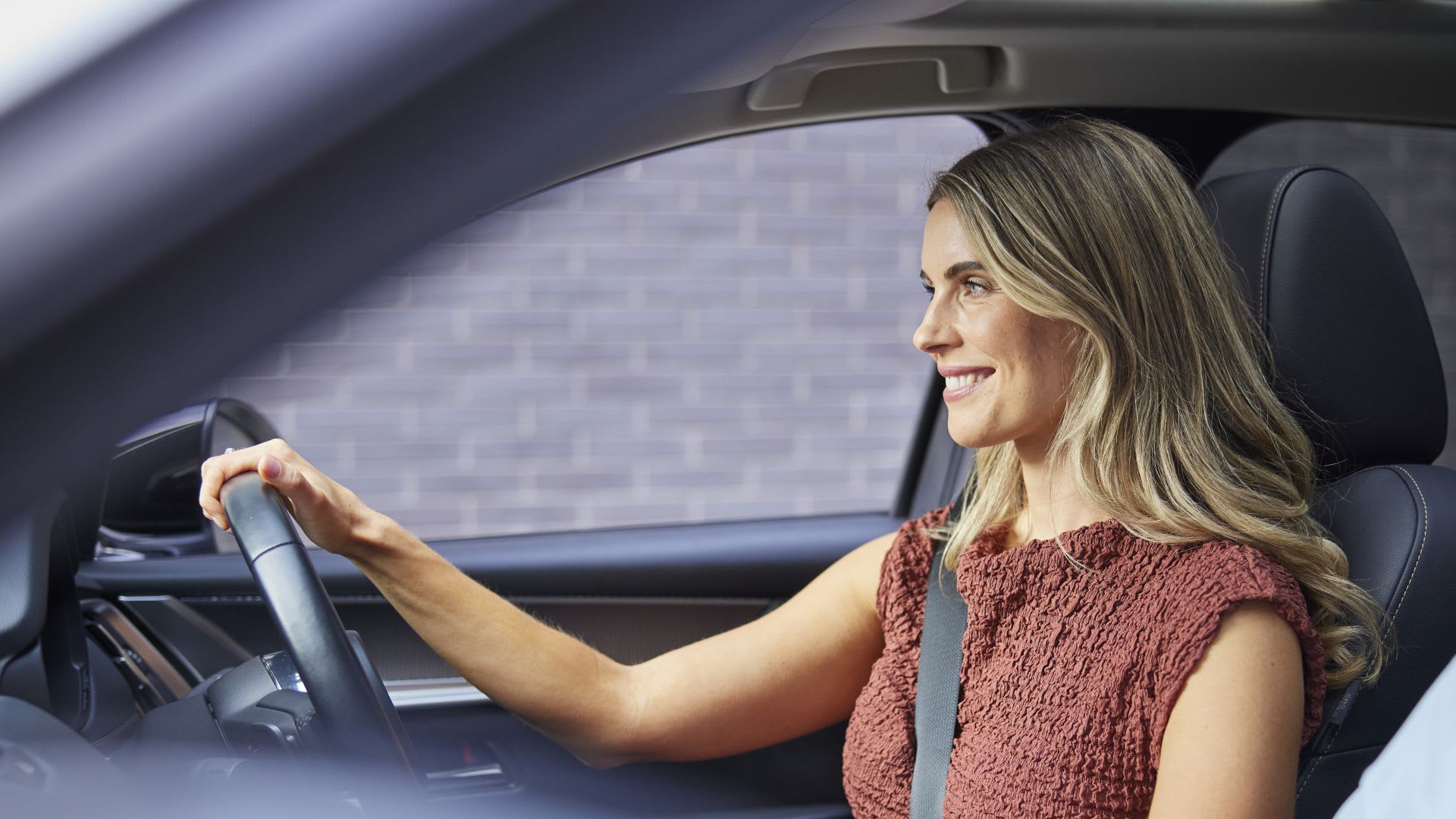 Woman in the driver's seat of her Mazda CX-60 SUV - view inside the car from the passenger seat
