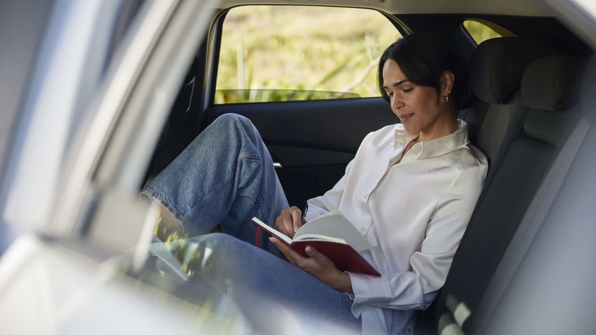 Interior view of a woman reading a book in the back seat of her Mazda CX-30 SUV