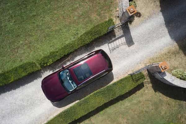 Drone shot looking down on an Artisan Red Mazda CX-80 7-seat hybrid SUV driving on a gravel road