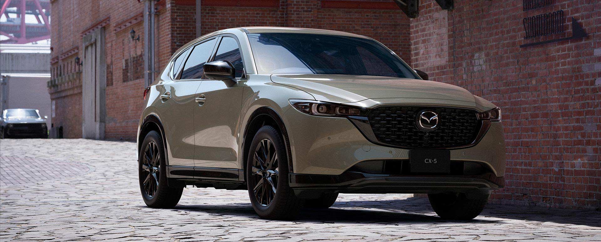 Front three-quarter view of a Zircon Sand Mazda CX-5 SUV parked on a city street