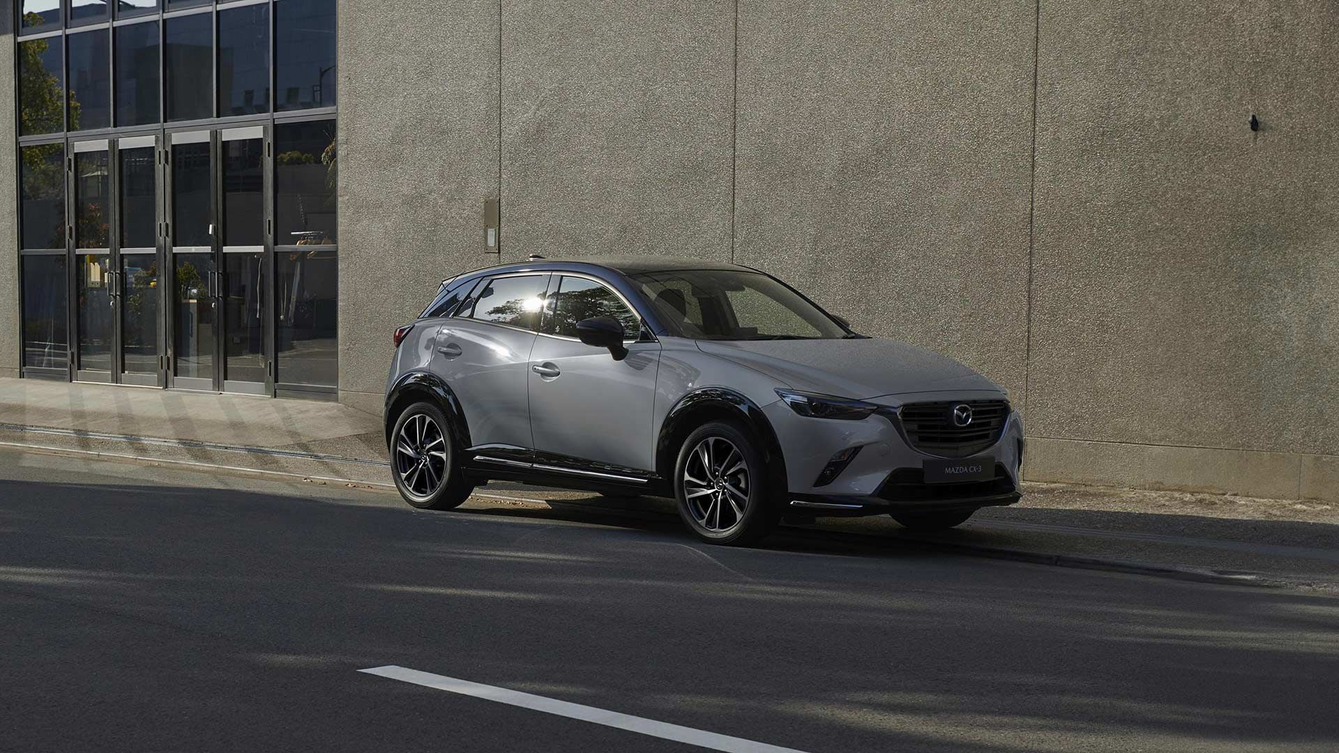 Front three-quarter view of a Ceramic Metallic Mazda CX-3 SUV parked on a city street