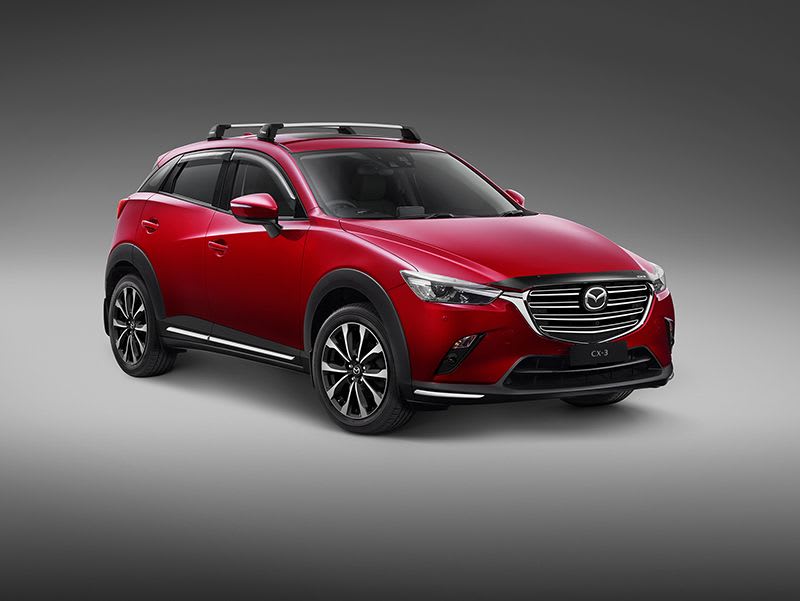 Front three-quarter studio image of a Soul Red Mazda CX-3 SUV fitted with roof racks accessories