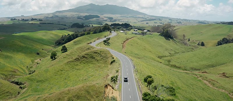 A road cutting through rolling green hills