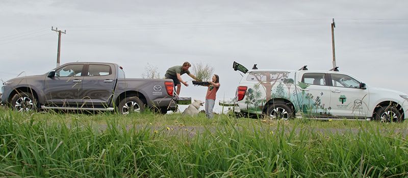 Two Mazda BT-50 uets parked back-to-back being loaded by a man and woman