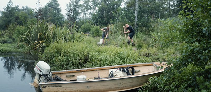 People working in a carbon sink with a tinny boat parked in the foreground