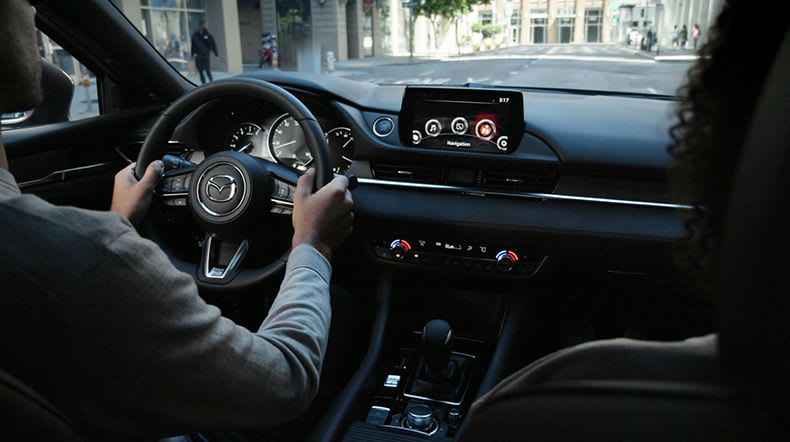 Man driving his Mazda car, looking out over the dashboard through the windscreen