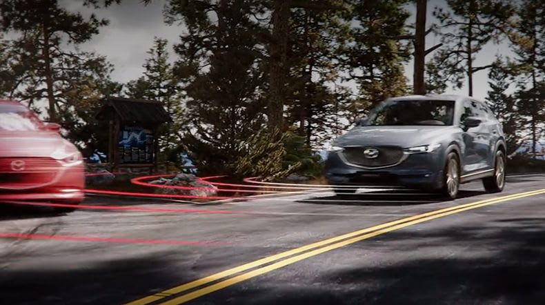 Two Mazda cars at an intersection with preventive safety radar graphics overlaid